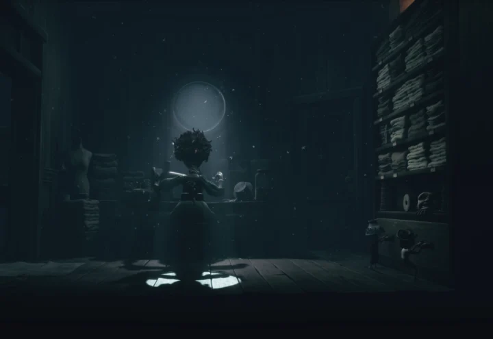 Capture d'écran du contenu additionnel de Little Nightmares III : The Backstage. Une couturière est à l'oeuvre, de dos, dans une pièce très sombre où seul une légère lumière provient d'une petite fenêtre, mettant en valeur la femme en plein travail.